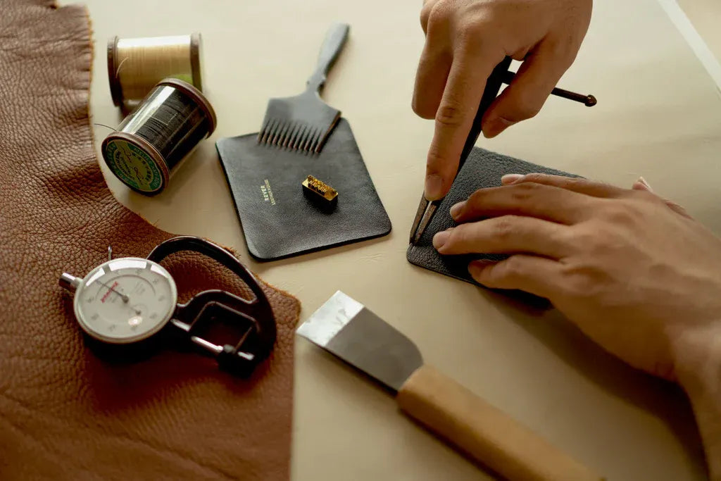 A craftsman creating a custom wallet as a unique corporate gift with his tools on the table