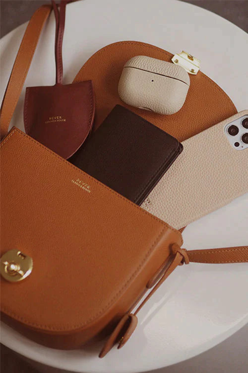 Huns Saddle Bag showing what it can hold — spacious leather crossbody bag.